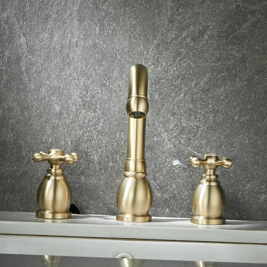 A close-up of the Allfixture Dual Handle Bathroom Sink Faucet set against a textured gray stone backdrop. This deck-mounted set features a central faucet with a curved spout and dual handles on either side, all in a polished brass finish, adding an elegant touch to your gold basin faucets setup.