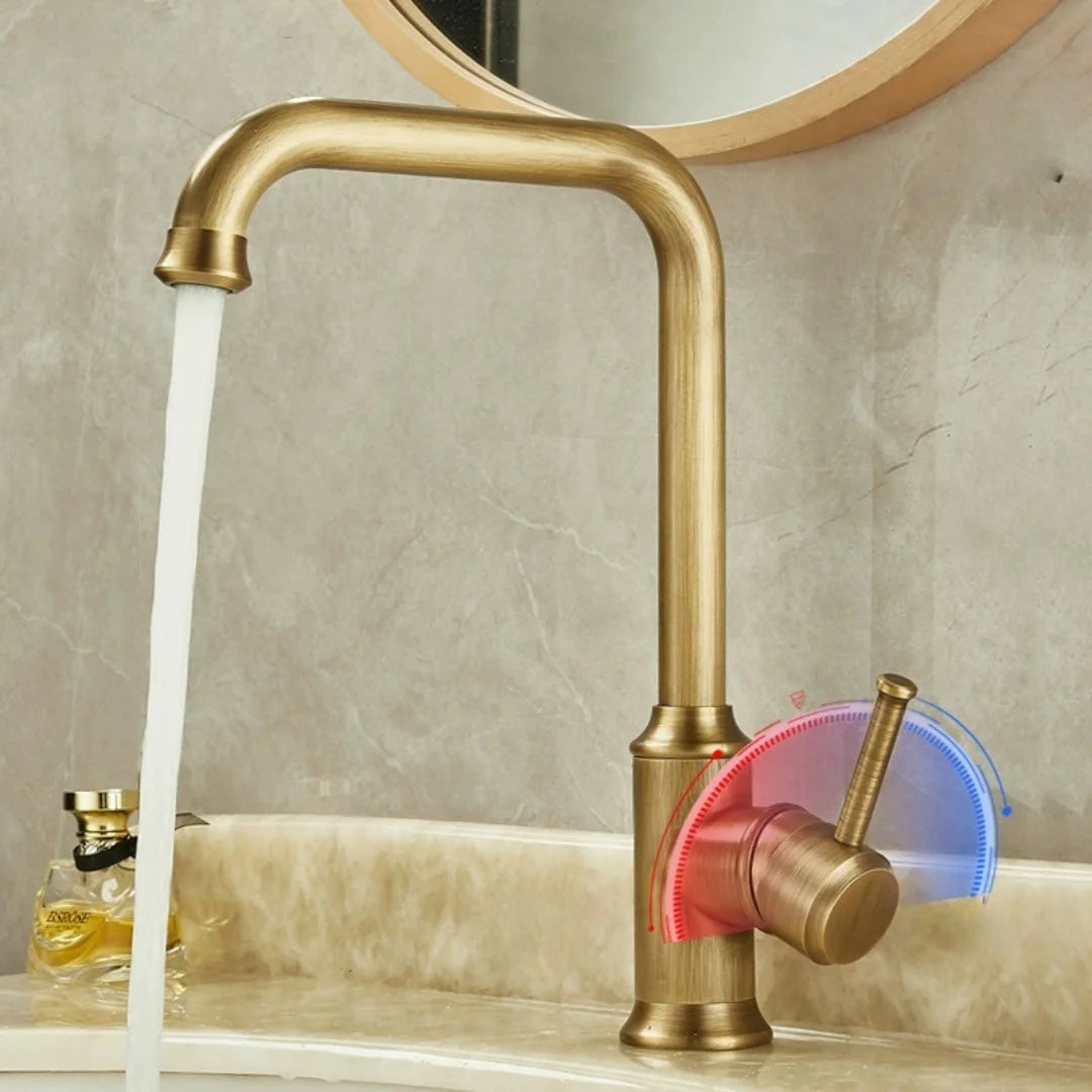 The AllFixture Maison Single Handle Bathroom Sink Faucet, made of solid brass, features blue and red temperature indicators on its lever handle and is shown with running water on a beige countertop next to a soap dispenser.