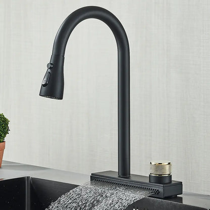 The kitchen sink is graced by the modern Rainfall Pull Out Spout Kitchen Faucet from Rozin, featuring a high-arc spout in a sleek matte black finish. Water cascades vertically from the front of the faucet in a flat stream. A gold-colored handle is prominently situated to the right of the base, while a potted plant peeks into view on the left.