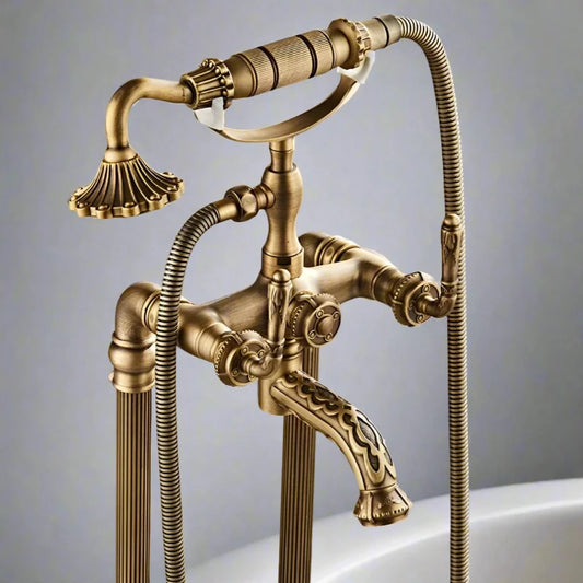 The Allfixture Antique Brass Carved Floor Standing Bathtub Faucet Tub Filler is a vintage-style set with intricate detailing. It features a handheld shower head with a floral design, a curved spout, and dual control knobs. Mounted on a tile wall, it exudes an antique yet contemporary luxurious aesthetic.