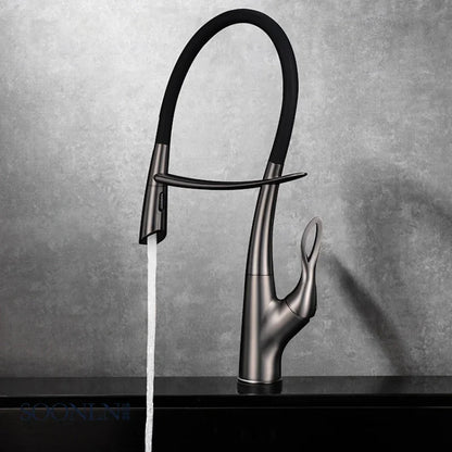 A Tiqui Single Handle Pull-Out Kitchen Faucet with a sleek, curved design is installed over a square, black sink. Water is flowing from the faucet, and the background features a minimalist setting with light-colored walls and a dark countertop.