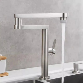 An Allfixture Deck Mounted Kitchen Faucet with Foldable Pot Filler is installed on a white counter. This modern faucet features a brushed gold finish, a single lever handle, and a tall, rectangular spout design with water flowing into the sink below. The background includes a light gray wall and part of another sink.