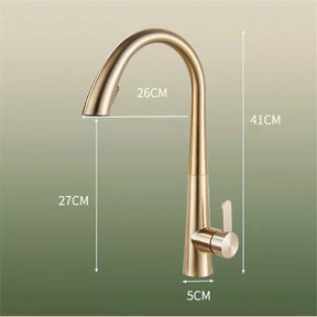 The Tiqui Single Lever Pull Out Spring Spout Faucet, featuring a sleek, curved design in brushed gold, is elegantly installed over a white sink. Water flows gracefully from the spout. The background showcases a white marble backsplash with subtle gray veining. Two white canisters with wooden lids sit on the counter, completing the sophisticated look.