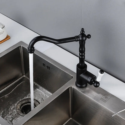 An Allfixture Single Handle Vintage Kitchen Sink Faucet, featuring a black finish and single hole design, is deck mounted on a white countertop above a stainless steel sink. Water flows gracefully from the faucet into the sink. The wall behind is gray, with a container holding kitchen utensils partially visible in the background.