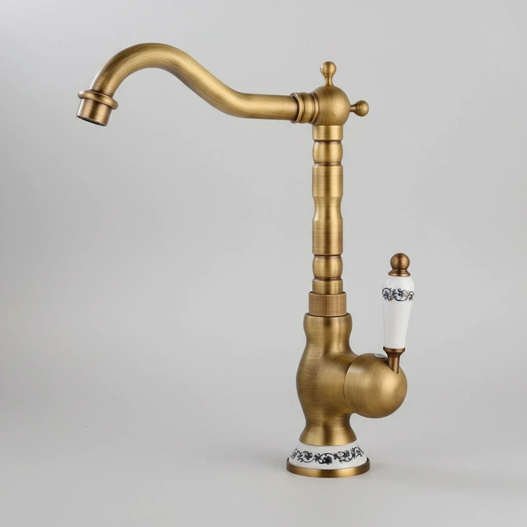 The AllFixture Heritage Brass Faucet features a curved spout and vintage-style white ceramic handle and base with black floral patterns, making it stand out against a plain light background.