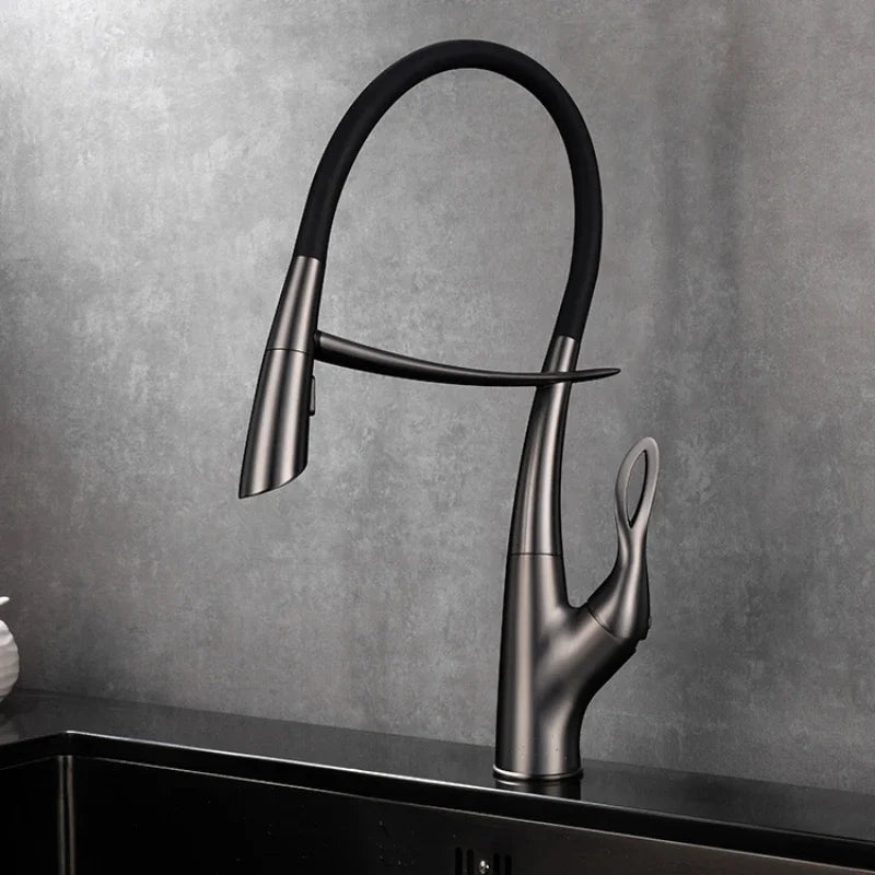 A Tiqui Single Handle Pull-Out Kitchen Faucet with a sleek, curved design is installed over a square, black sink. Water is flowing from the faucet, and the background features a minimalist setting with light-colored walls and a dark countertop.