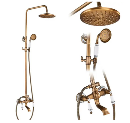 A wall-mounted Rozin Antique Brass Complete Shower Faucet Set with dual handles and white ceramic accents, labeled 'H' for hot and 'C' for cold. Water flows from the spout into a sink below, with flexible metal hoses connected to the faucet. The background is a gray tiled wall.