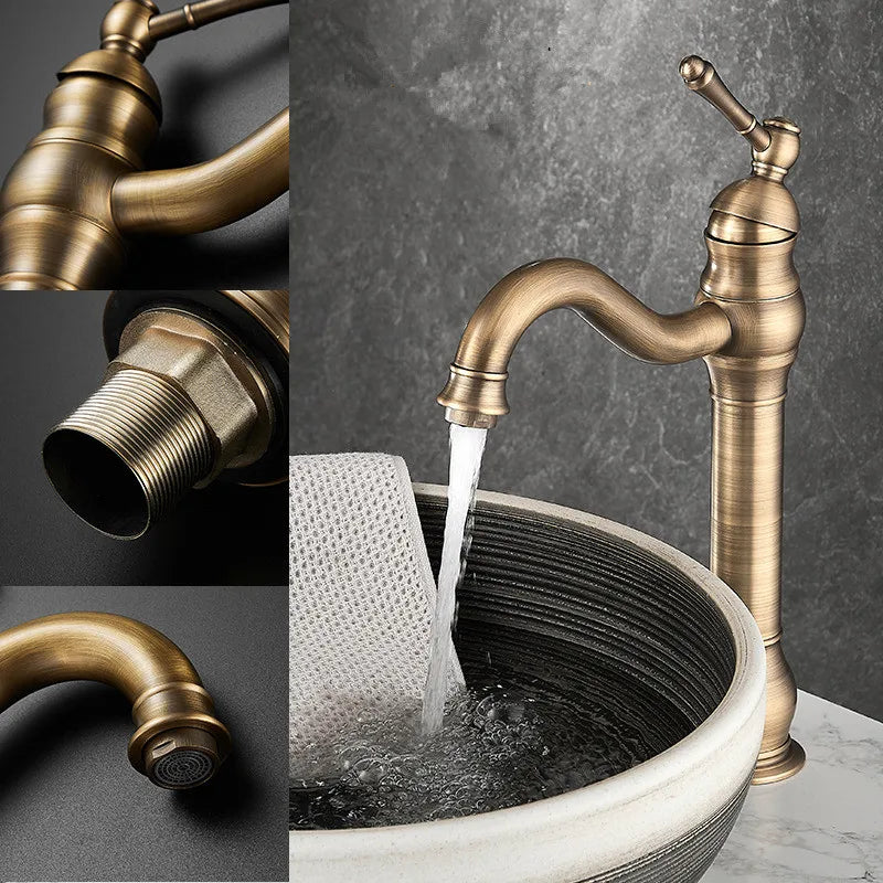 An Allfixture Deck Mounted Antique Brass Bathroom Faucet with an elegant curved spout and single handle stands beside a round, textured stone sink. Featuring a hot and cold water mixer, the tall, dark bronze faucet perfectly complements the folded beige towel draped over the sink edge against a dark gray marble wall and white marble countertop.