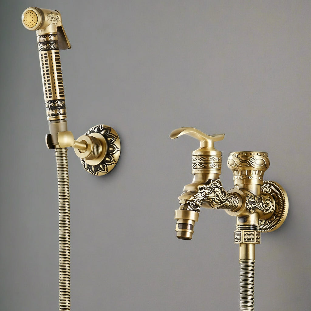 The AllFixture Heritage Toilet Sprayer & Bidet Faucet Set showcases a polished gold, intricately patterned, dual-handle wall-mounted tap and flexible hose bidet sprayer against a plain gray background.