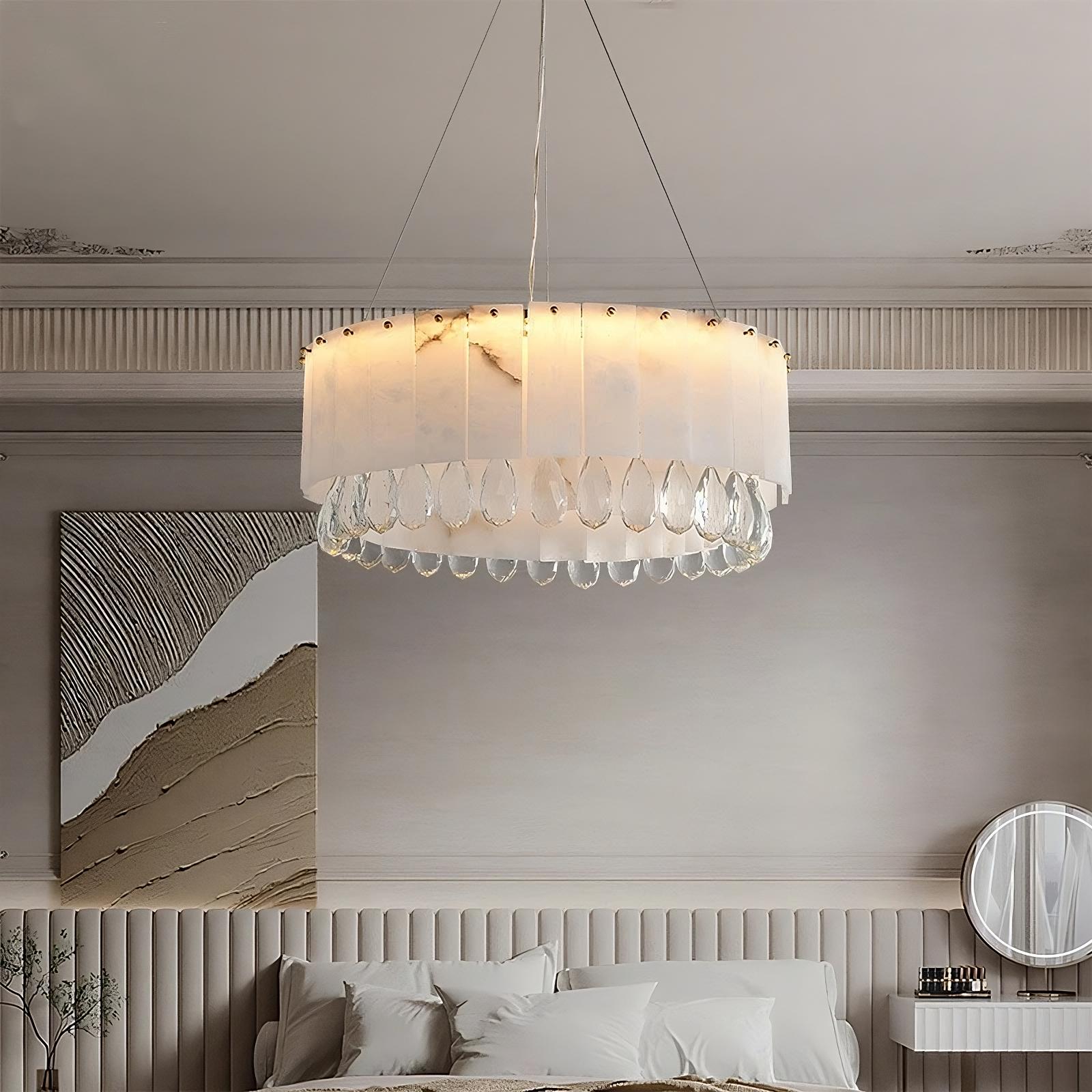 A modern bedroom features a large, circular *Marble & Crystal Modern Chandelier* from Morsale.com with translucent, droplet-shaped pendants. The room has a neutral color palette with a textured wall, an abstract painting above the bed, and a round mirror on the vanity, epitomizing *luxury home decor*.