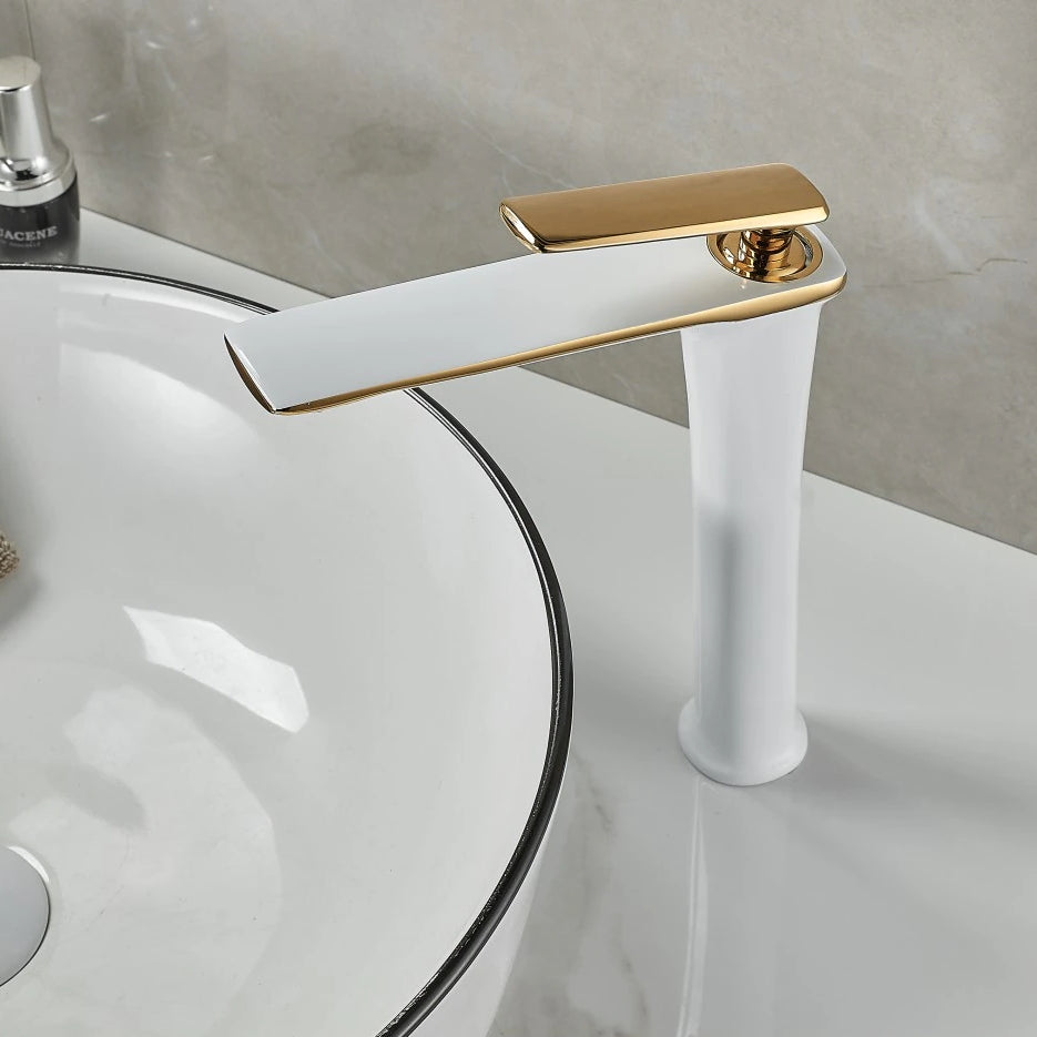 The Becola™ Single Handle Bathroom Faucet, with its modern matte black and rose gold finish, stands next to a white ceramic basin sink featuring a metallic rim. The faucet's sleek design includes a long, high arch and a lever handle. The background showcases light grey tiled walls.