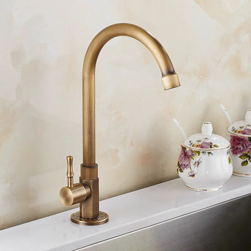 A Single Handle Antique Brass Kitchen Faucet by ZGRK, featuring a high-arc spout and single lever handle, is mounted on the countertop. In the background, floral patterned porcelain containers are set against a marbled beige backsplash, exuding an elegance reminiscent of bathroom faucets.