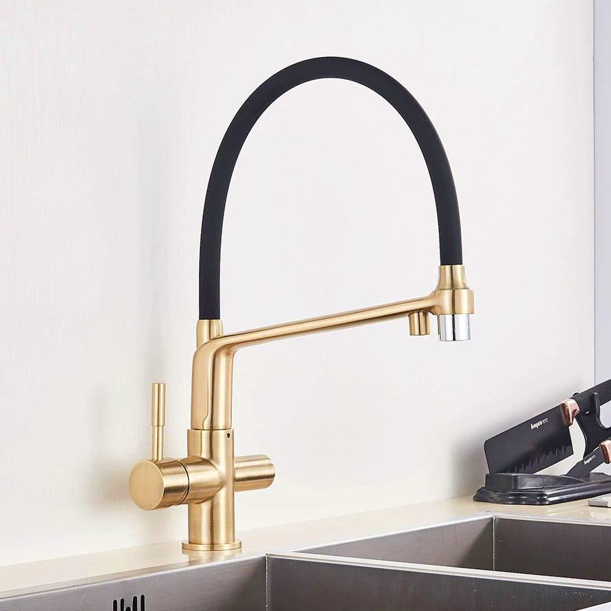 An allfixture Brushed Gold Solid Brass Kitchen Faucet With Purified Water Tap, featuring a sleek gold finish and a flexible black hose, is installed over a stainless steel sink. The faucet has a single lever handle and a high-arching spout, providing it with a contemporary and stylish design.