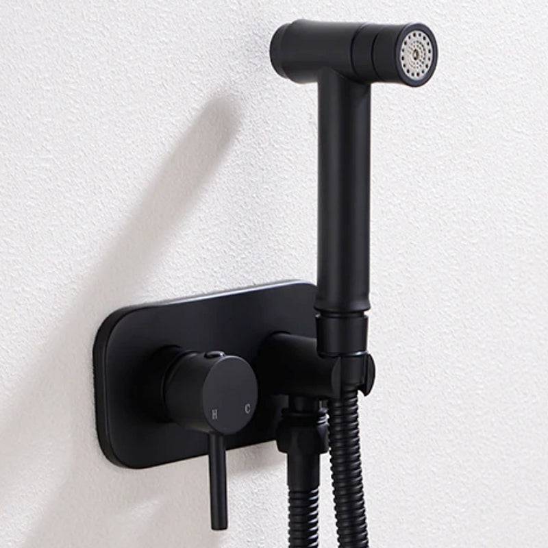 The Wasser™ Brass Handheld Toilet Sprayer by Morsale.com is mounted on a wall next to a control handle and hose, seamlessly blending with nearby bathroom faucets. The sleek design of the sprayer includes a modern finish, with the control mechanism integrated into the wall mount.