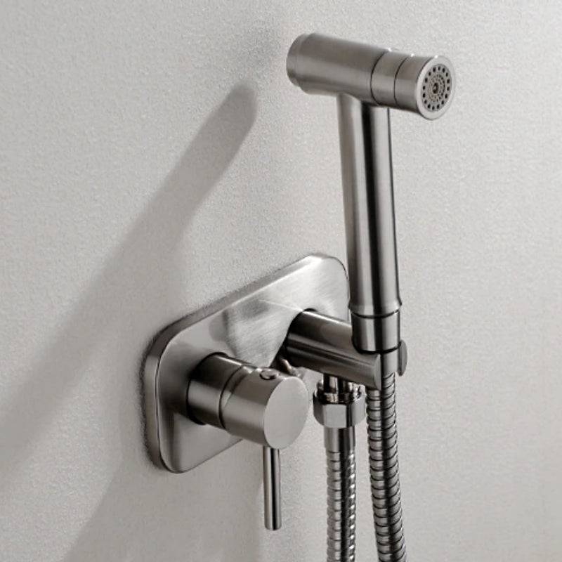 The Wasser™ Brass Handheld Toilet Sprayer by Morsale.com is mounted on a wall next to a control handle and hose, seamlessly blending with nearby bathroom faucets. The sleek design of the sprayer includes a modern finish, with the control mechanism integrated into the wall mount.