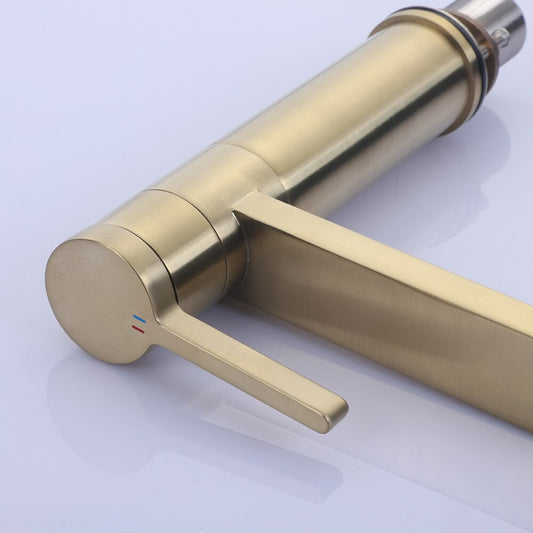 A modern ROZIN Brushed Gold Single Handle Faucet by allfixture is mounted on a white bathroom sink, with water flowing from it. A folded beige towel is placed on the left corner of the sink. The background features white tiled walls, adding a touch of elegance akin to a sophisticated kitchen faucet.