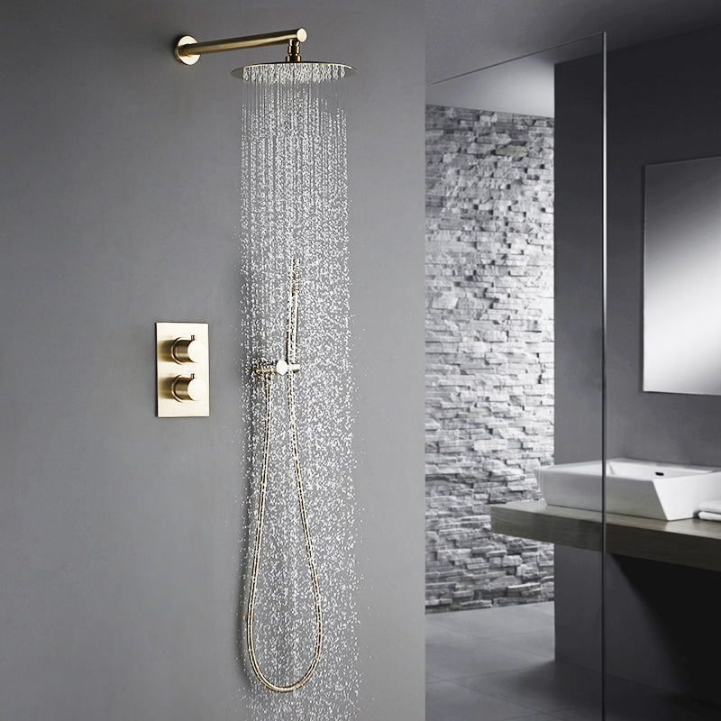 A modern bathroom featuring the Wasser™ Solid Brass Complete Shower System from Morsale.com, with a sleek rainfall showerhead mounted on a gray wall and a matching handheld shower faucet attached. Water cascades down as the shower is turned on. The room showcases a minimalist design with a white sink and a stone accent wall in the background.