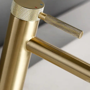 The allfixture Solid Brass Single Handle Bathroom Sink Faucet, featuring a modern gold-toned finish, cylindrical base, and sleek side-mounted handle, is shown. Water flows steadily from the spout into a white basin filled with water, creating ripples. The background is plain and neutral.