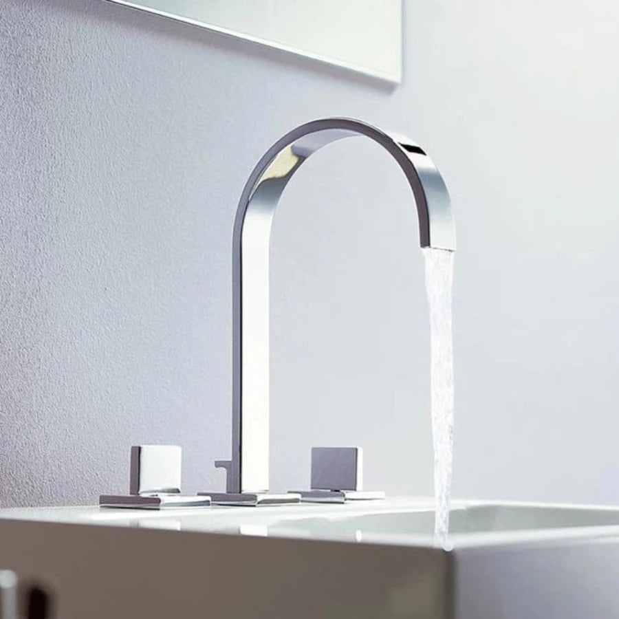 A minimalist black sink faucet from AllFixture, featuring an arching design, is mounted on a white countertop. The Double Handle Deck Mounted Faucet includes two lever handles—one on each side—with subtle red and blue indicators for hot and cold water respectively. In the background, a white window sill completes the scene.