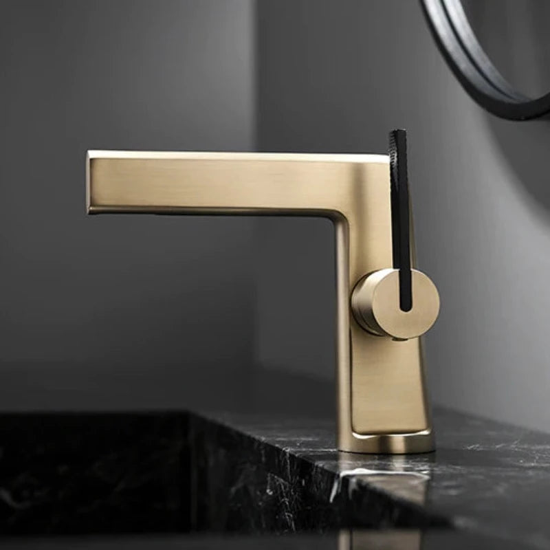 A close-up of the Mike Jake Single Handle Solid Brass Bathroom Basin Faucet, featuring a contemporary matte gold finish and an elegant black lever handle. Positioned over a dark marble sink in a modern bathroom with neutral-colored walls, this fixture seamlessly complements the overall design, showcasing the sophisticated allure typical of premium bathroom faucets.