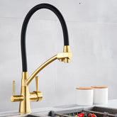 Over a stainless steel sink, the Solid Brass Kitchen Faucet With Purified Water Tap from allfixture takes center stage with its sleek, gold finish and flexible black hose. The background boasts a grey backsplash and two white canisters with wooden lids on the countertop, echoing the elegance of premium bathroom faucets.