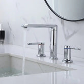 A modern bathroom sink features water flowing from the Solid Brass Deck Mounted Bathroom Sink Faucet by Morsale.com into a white basin. The countertop is crafted from white marble, and there are two matching chrome handles flanking the faucet. A round mirror and toiletries are visible in the background, creating an elegant ambiance reminiscent of a stylish kitchen faucet.