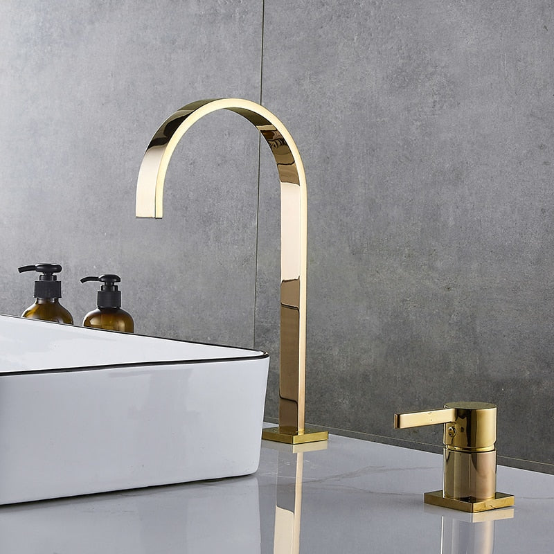 A modern bathroom sink with a rectangular white basin featuring black trim is shown. Water flows from AllFixture's sleek, U-shaped, rose gold Single Handle Deck Mounted Bathroom Faucet. Additionally, a matching rose gold lever handle and soap dispenser are visible on the gray countertop—perfect for coordinating with any stylish bathroom sink faucet or shower head.