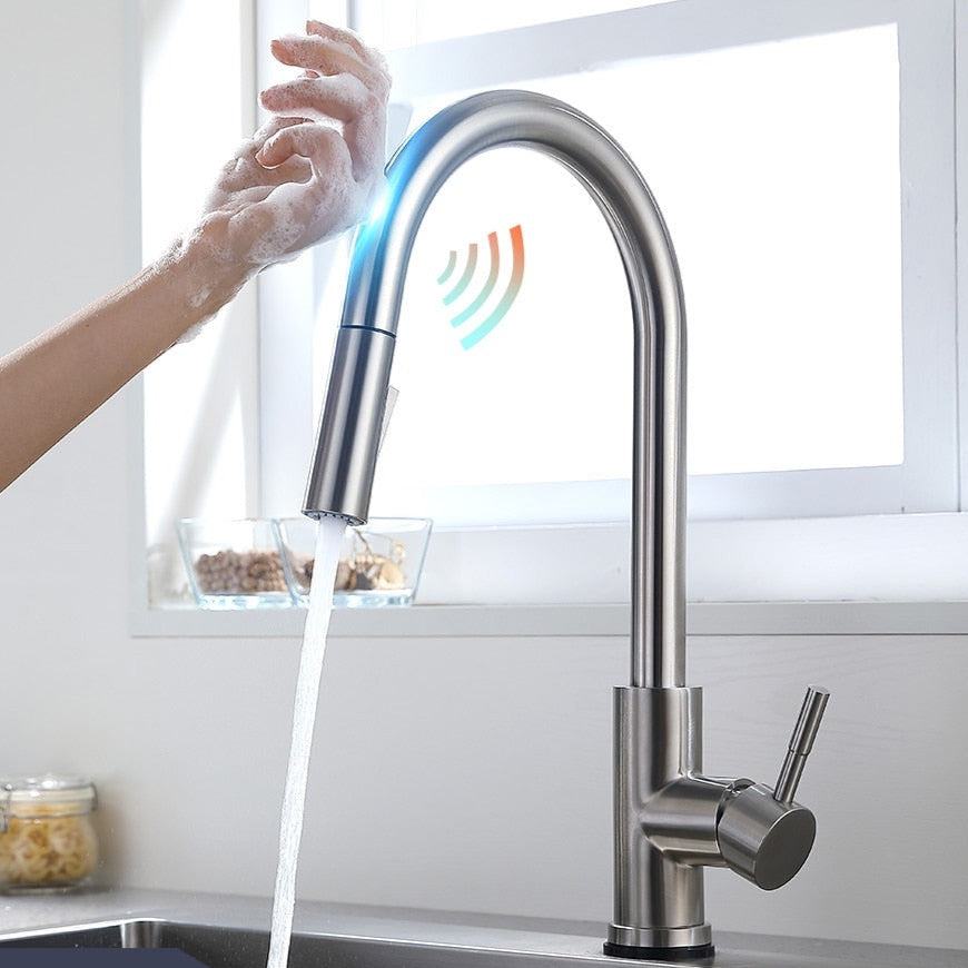 The allfixture Stainless Steel Smart Touch Pull Out Kitchen Faucet, featuring a high arch spout and a pull-down spray head, is mounted on a sleek stainless steel sink, dispensing a stream of water. Flanked by two white containers with wooden lids against a muted gray background, it creates an elegant and functional kitchen space.