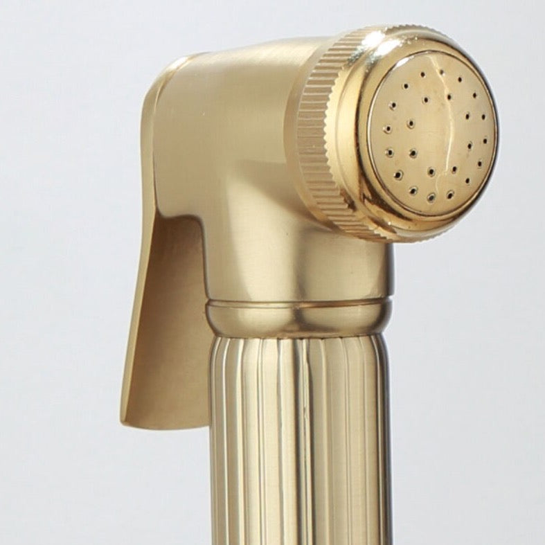 An elegant **Wall-Mounted Brass Handheld Sprayer** by **AllFixture**, featuring a sleek minimalist design with vertical lines for grip, is installed against a white marble background. The modern gold-colored set includes a handheld shower head and hose, creating a stylish addition to the bathroom.