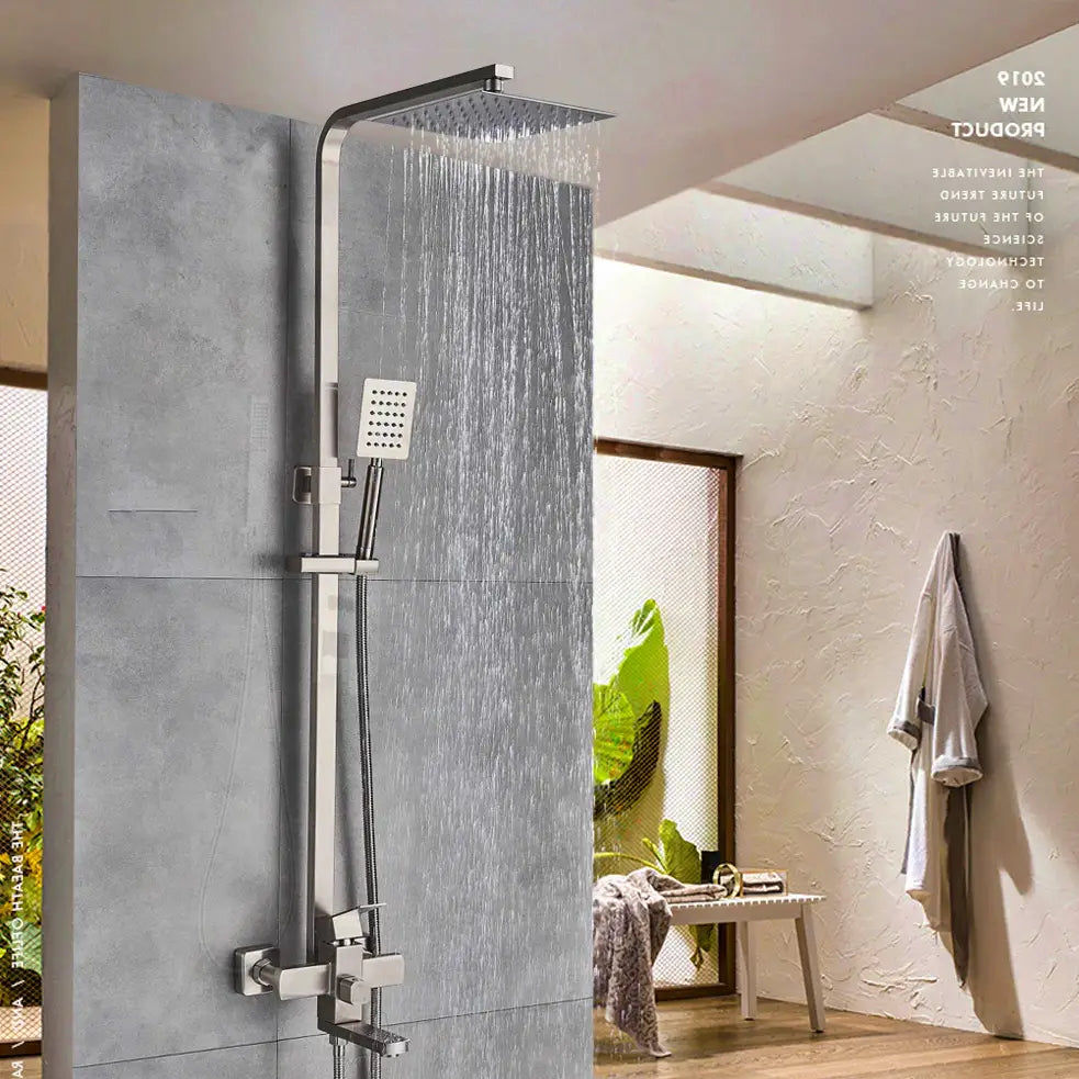 A modern bathroom featuring the AllFixture Solid Brass Rainfall Bath Shower System with a gold-finished square rain shower head and an adjustable handheld showerhead, all mounted on a gray tiled wall. A towel hangs on the adjacent white textured wall, and a glass door opens to a sunlit room, accentuating the elegant design of the shower faucet.