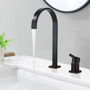 A modern bathroom sink with a rectangular white basin featuring black trim is shown. Water flows from AllFixture's sleek, U-shaped, rose gold Single Handle Deck Mounted Bathroom Faucet. Additionally, a matching rose gold lever handle and soap dispenser are visible on the gray countertop—perfect for coordinating with any stylish bathroom sink faucet or shower head.