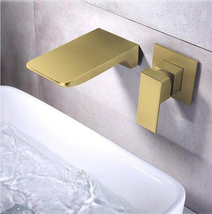 An opulent Solid Brass Wall Mounted Waterfall Faucet by AllFixture pours water into a white sink set against a marble backsplash. This modern, gold faucet boasts a flat spout and a matching lever handle. The flowing water is clear and steady, enhancing the bathroom's elegant and luxurious ambiance.