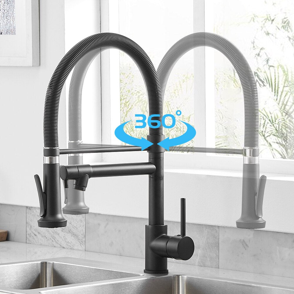 An AllFixture Single Handle Double Spout LED Kitchen Faucet with a sleek, modern black finish and a flexible spring neck dispenses water into a transparent glass. The faucet is mounted on a black countertop, set against wooden panels in the background. Natural light streams through a window framed in black in the background.