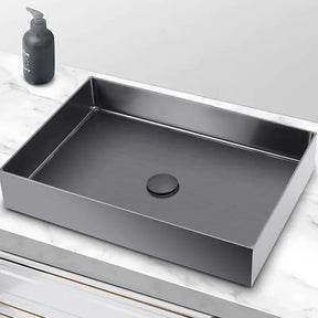 A modern rectangular sink, the Mike Jake SUS304 Stainless Steel Rectangle Bathroom Sink in Gunmetal, sits on a marble countertop. The sink, with its matte black finish and centered drain cover, is complemented by a sleek kitchen sink faucet. To the left of the sink is a black soap dispenser. The countertop features clean, white marble with subtle gray veining.