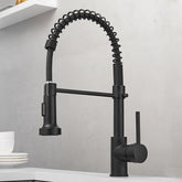 A contemporary Pull Out Spring Spout Kitchen Faucet by AllFixture, featuring a matte black finish, coiled spring neck, pull-down spray head, and single lever handle, is installed on a light-colored counter. Positioned near white dishes and set against a neutral gray wall background, this stylish fixture seamlessly complements bathroom faucets in modern homes.