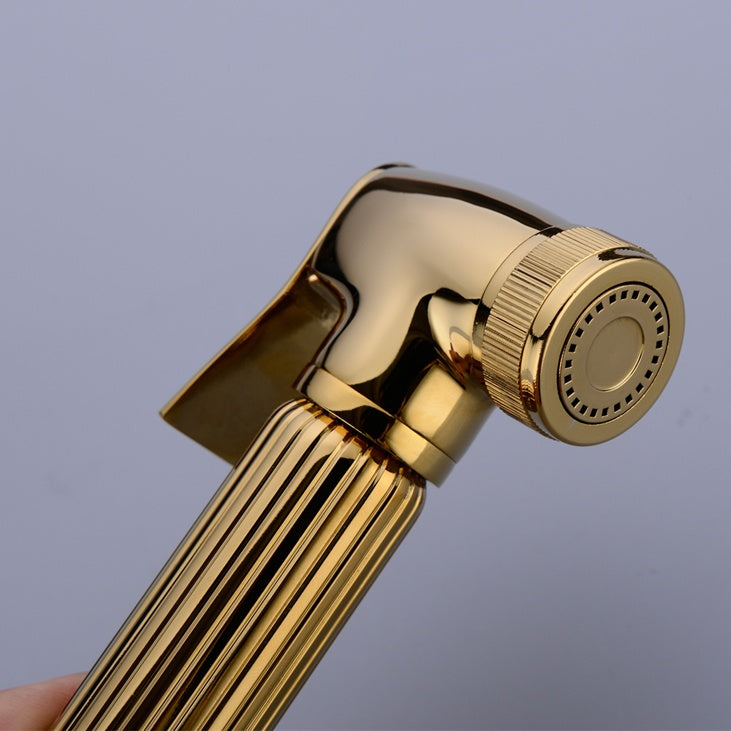 A hand holding the Wasser™ Solid Brass Handheld Toilet Sprayer by allfixture, attached to a matching wall-mounted fixture, much like elegant bathroom faucets. Water is spraying from the sprayer, and the scene is set against a light-colored backdrop.