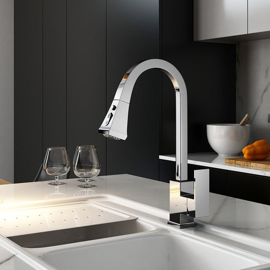 A modern kitchen features the Wanfan Solid Brass Pull Out Kitchen Faucet by allfixture, characterized by its sleek, high-arc chrome design. The contrasting aesthetic is created by a black backsplash and a white countertop. Two wine glasses and a white bowl filled with oranges are placed on the counter, illuminated by natural light from a nearby window.