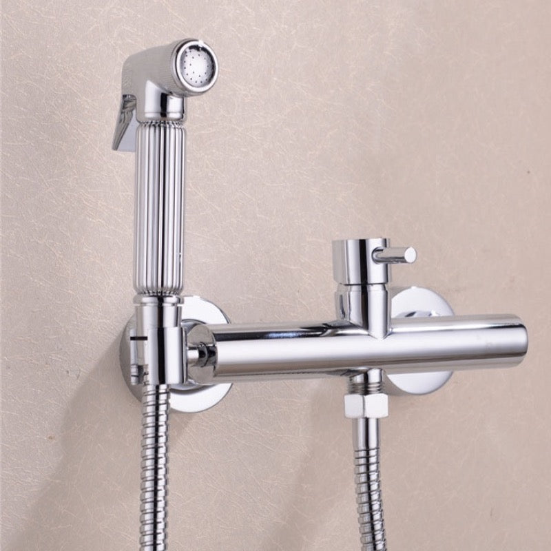 A hand holding the Wasser™ Solid Brass Handheld Toilet Sprayer by allfixture, attached to a matching wall-mounted fixture, much like elegant bathroom faucets. Water is spraying from the sprayer, and the scene is set against a light-colored backdrop.