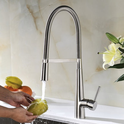 A person rinses fresh green lettuce under an allfixture Pull Down 2 Function Sprayer Brass Kitchen Sink Faucet with a tall, flexible design and pull-down spray head. The stainless steel faucet features a single lever handle, and the water flows into a white sink beneath.