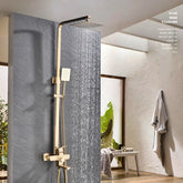 A modern bathroom featuring the AllFixture Solid Brass Rainfall Bath Shower System with a gold-finished square rain shower head and an adjustable handheld showerhead, all mounted on a gray tiled wall. A towel hangs on the adjacent white textured wall, and a glass door opens to a sunlit room, accentuating the elegant design of the shower faucet.