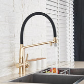 A modern kitchen sink with the sleek, gold-toned Solid Brass Kitchen Faucet With Filtered Water Tap by allfixture, featuring a black curved spout. The faucet is turned on, with water flowing over fresh produce in a stainless steel sink. In the background, there's a white brick wall and partially open window blinds.