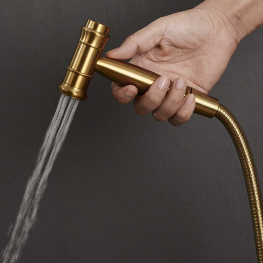 A hand holding the allfixture Wasser™ Solid Brass Hot & Cold Water Bidet Faucet with water flowing from the nozzle, reminiscent of a sleek shower head, against a dark background.