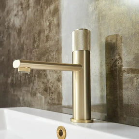 The Wanfan Knob Switch Solid Brass Bathroom Faucet showcases a modern design with a brushed gold finish. This cylindrical faucet features a textured single handle on top for precise temperature and water flow control, complemented by a sleek, straight spout extending horizontally from the base.