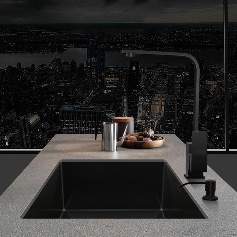 An AllFixture 304 Stainless Steel Undermount Kitchen Sink featuring a sleek black kitchen faucet and soap dispenser in a matching finish, installed in a white countertop. To the right, there are jars with seasonings and sauces, and the corner of a cutting board is visible. The rectangular sink includes a silver drain.