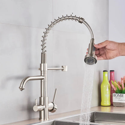 A MyQualife Double Handle Pull-Out Spout Kitchen Faucet with a high, curved design and flexible spring installation is installed over a stainless steel sink. The kitchen faucet features a versatile pull-out spray head and dual lever handles for water control. In the background, colorful bottles adorn the counter.