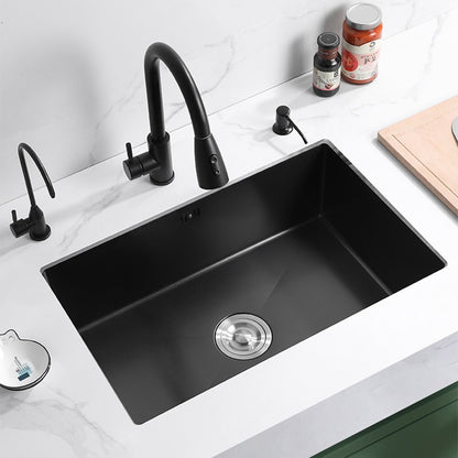 An AllFixture 304 Stainless Steel Undermount Kitchen Sink featuring a sleek black kitchen faucet and soap dispenser in a matching finish, installed in a white countertop. To the right, there are jars with seasonings and sauces, and the corner of a cutting board is visible. The rectangular sink includes a silver drain.