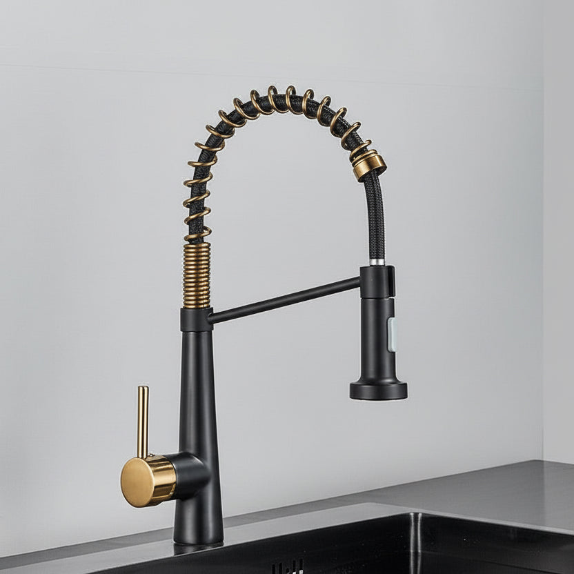The AllFixture Deck Mounted Pull Down Sprayer Kitchen Sink Faucet features a modern black and gold finish, flexible coiled spring design, single lever handle, and pull-down sprayer, installed on a black sink against a light gray wall.