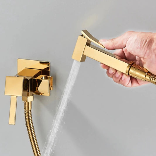A hand holds the Morsale.com Wall-Mounted Toilet Sprayer Bidet Faucet in gold, spraying water from its nozzle while attached to a matching valve, set against a light gray background.