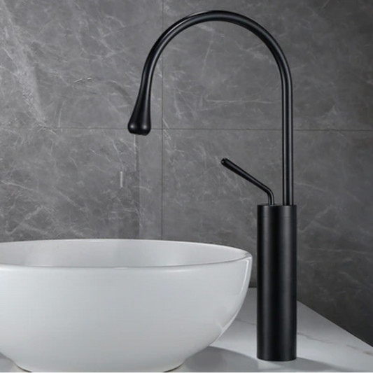 A modern bathroom featuring a white ceramic vessel sink paired with the Tiqui™ Single Handle Bathroom Sink Faucet in matte black by Tiqui. The wall behind boasts gray marble-patterned tiles, crafting a clean and minimalist aesthetic.