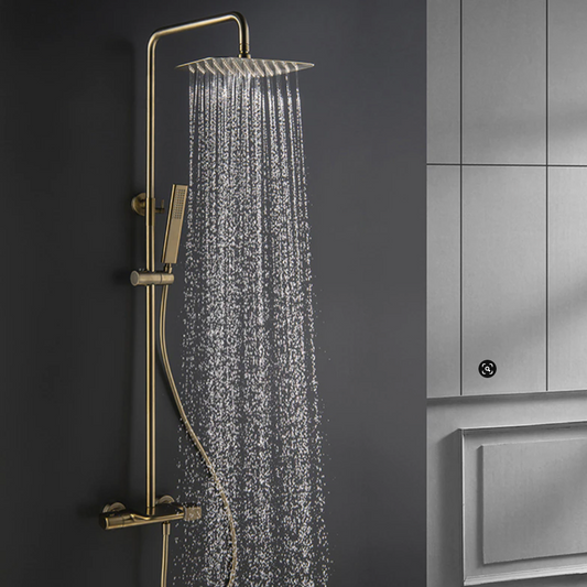 The bathroom boasts a sophisticated shower setup, showcasing the Mike Jake Solid Brass Shower Mixer with Bathtub Faucet and a handheld shower wand against a dark gray wall. Water cascades from the brass rain shower head, creating droplets that glisten in the light. A sleek sink faucet adds to the modern aesthetic, while light gray cabinets provide an elegant backdrop.